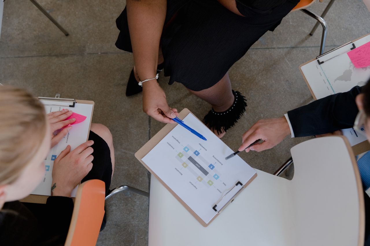 Top view of colleagues discussing and brainstorming ideas with clipboards in a meeting.